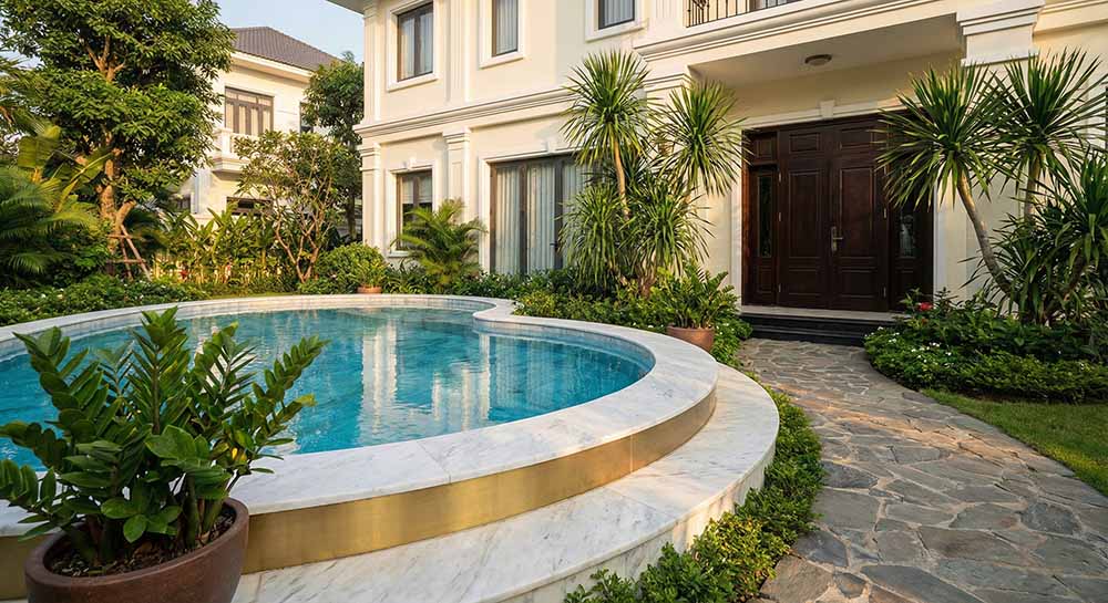 Mẫu thiết kế hồ bơi hình tròn phong thủy đặt trước biệt thự, viền đá trắng kim loại tượng trưng cho hành Kim sinh Thủy thu hút tài lộc_